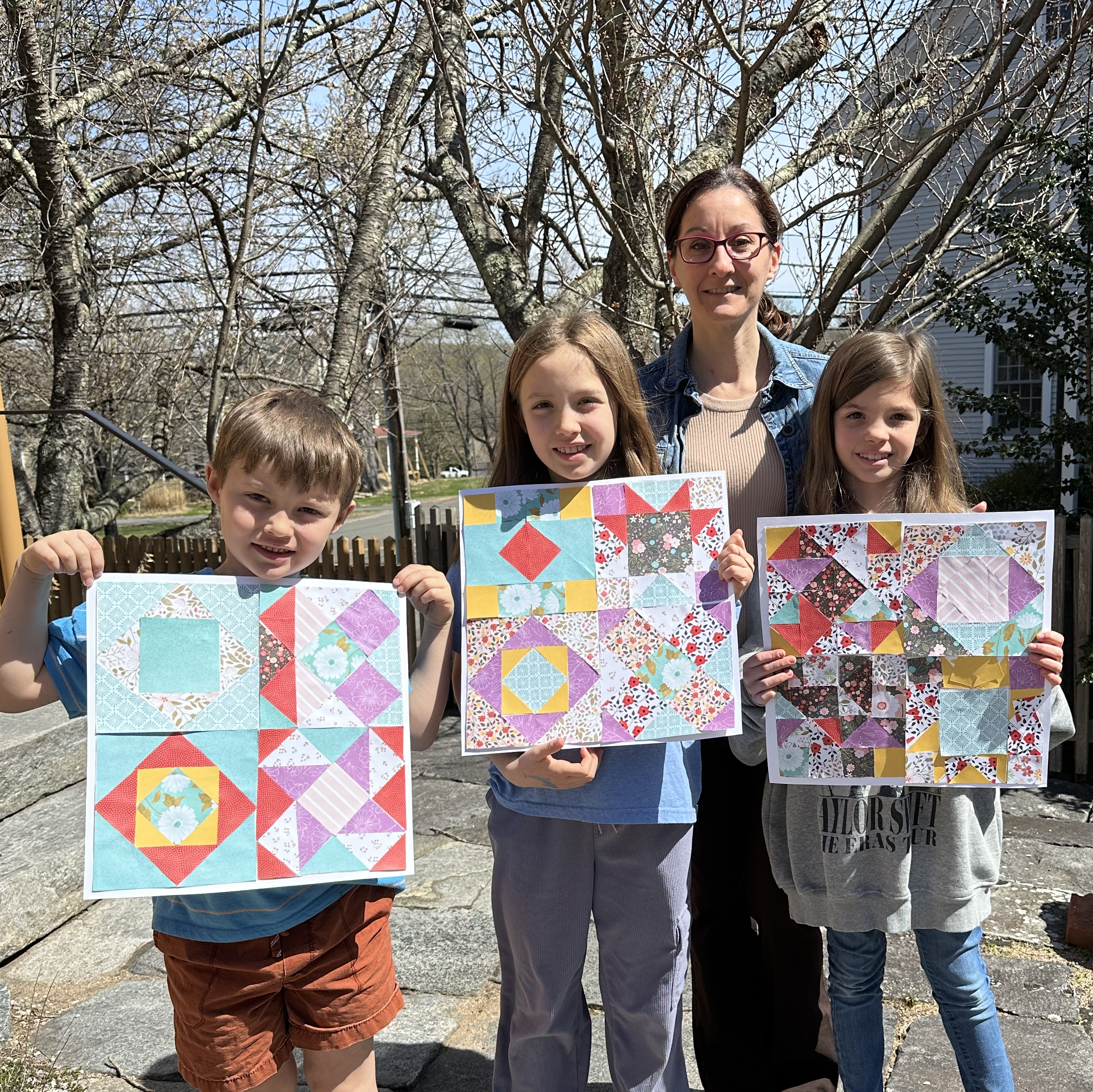 Three children showing off their paper quilt projects.